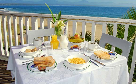 Café da manhã é servido ao ar livre, com vista para o mar