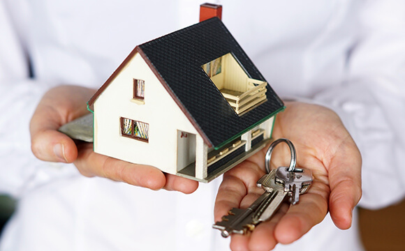 Imagem de uma pessoa segurando uma pequena casa e chaves
