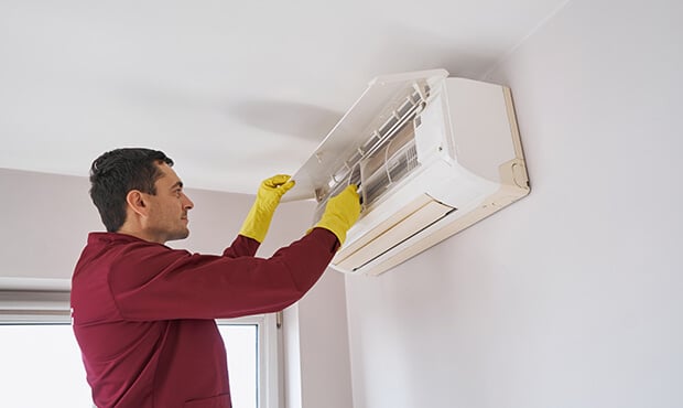Imagem de um homem instalando um ar-condicionado