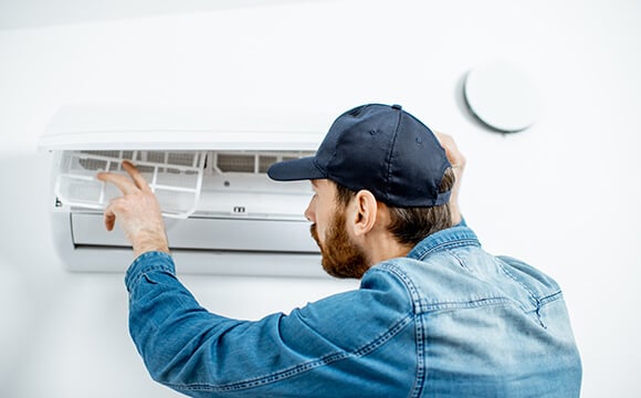Imagem de um homem instalando um ar-condicionado