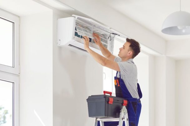 Instalador subindo em uma escada para realizar a montagem e conexões da evaporadora, seguindo as dicas de como instalar ar-condicionado.