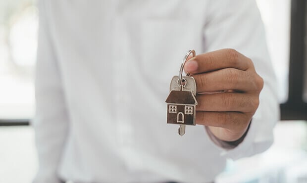 Imagem de uma pessoa segurando uma chave com chaveiro de casa