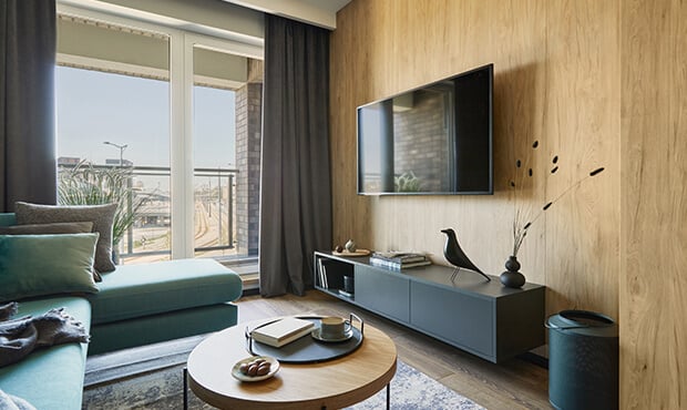 Imagem da sala de um apartamento pequeno com rack, TV, sofá e mesa de centro