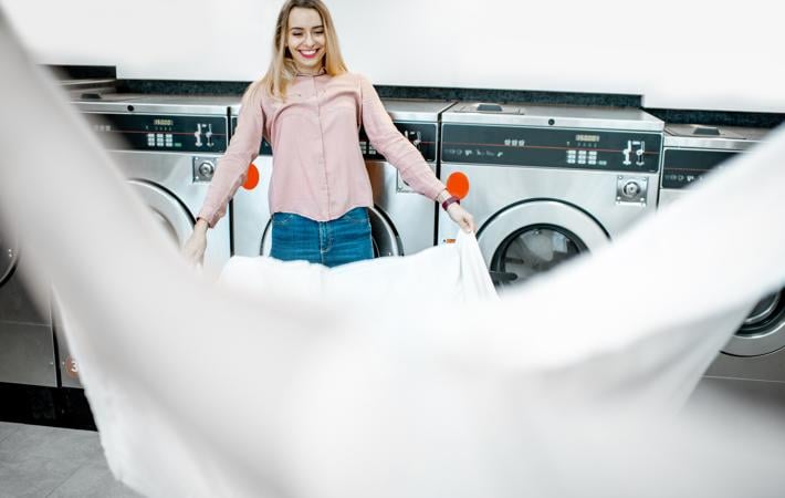 Pessoa em lavanderia estendendo lençol