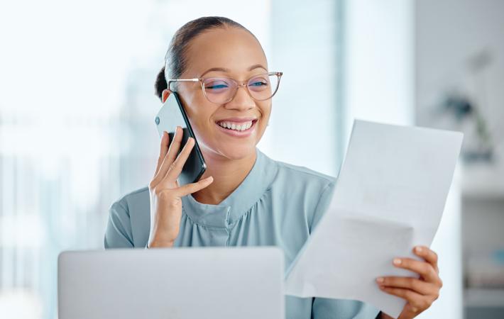 Mulher falando no telefone olhando papel