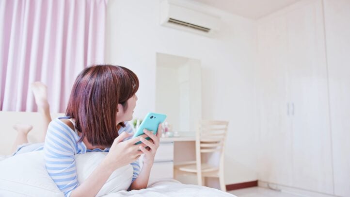 Mulher confortável termicamente em seu quarto, pois os btus metros quadrados do seu ar-condicionado estão corretos.