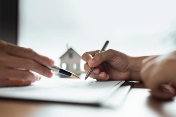 Duas pessoas analisando documentos para vender imóvel com segurança