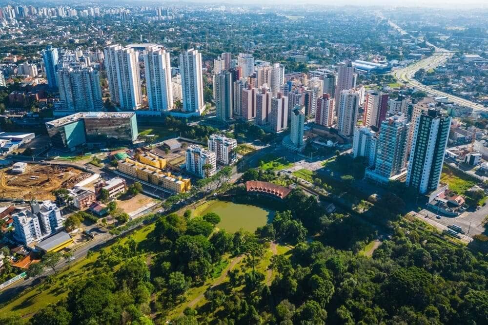 Vista aérea de Curitiba, mostrando ser uma cidade bem arborizada e com vários prédios.