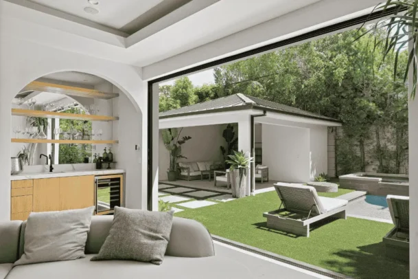 Área gourmet em edícula no quintal com espaço de convivência e piscina ao lado da casa principal.