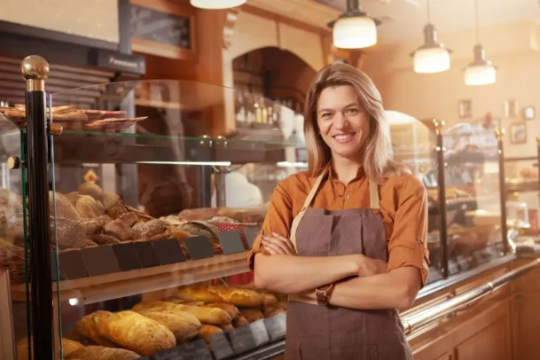 Mulher em frente à vitrine de pães em uma padaria de SP.