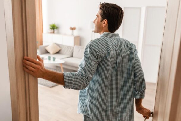 Homem na porta de uma casa olhando feliz para dentro
