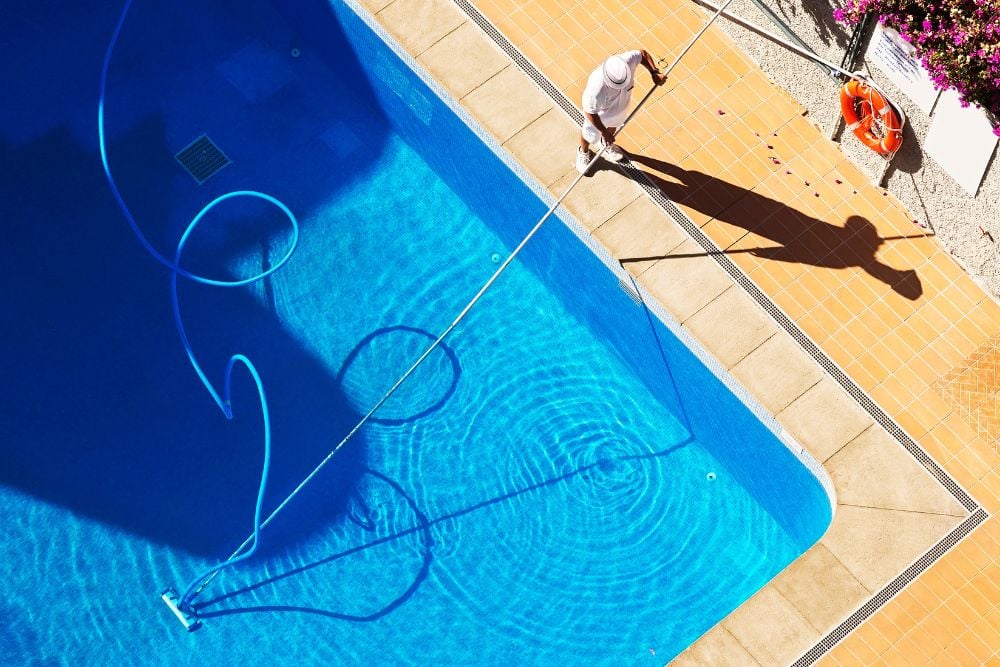 como limpar piscina: homem limpa a piscina.