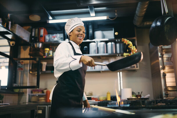 Chef sorridente preparando refeição. Onde comer em SP.