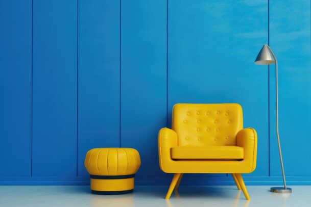 Poltrona amarela vibrante e pufe combinando em um quarto com parede azul, demonstrando o alto contraste das cores complementares e sua aplicação dinâmica