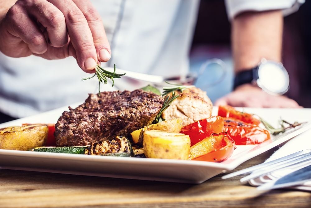 Prato sofisticado sendo finalizado por chef de cozinha, representando a gastronomia refinada dos melhores restaurantes de Curitiba