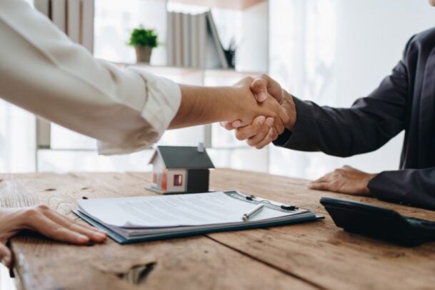 Duas pessoas apertando as mãos após fechar negócio, ilustrando o acordo firmado com o seguro fiança em contratos de locação.