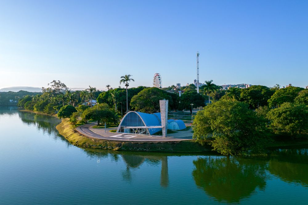 Vista aérea do Conjunto Moderno da Pampulha em Belo Horizonte, com a icônica Igreja São Francisco de Assis de Niemeyer na ilha e a Lagoa da Pampulha ao redor. Perfeito para quem busca o que fazer em Belo Horizonte com arquitetura e beleza natural.