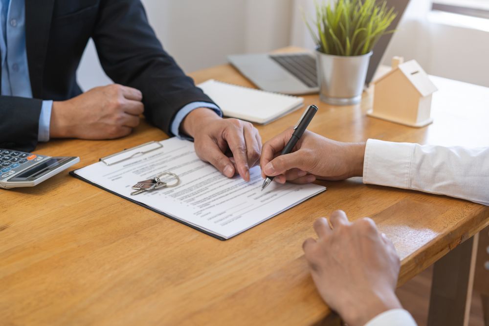 Caução aluguel: pessoa assinando contrato de locação em uma mesa de escritório, formalizando o acordo de depósito caução.
