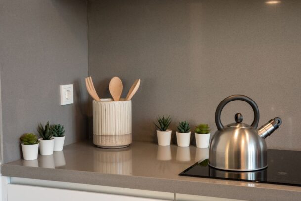 Chaleira moderna e utensílios básicos em um porta-talheres na bancada, itens essenciais para a lista de chá de cozinha.