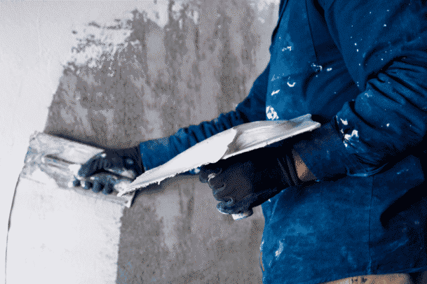 um homem passando gesso na parede