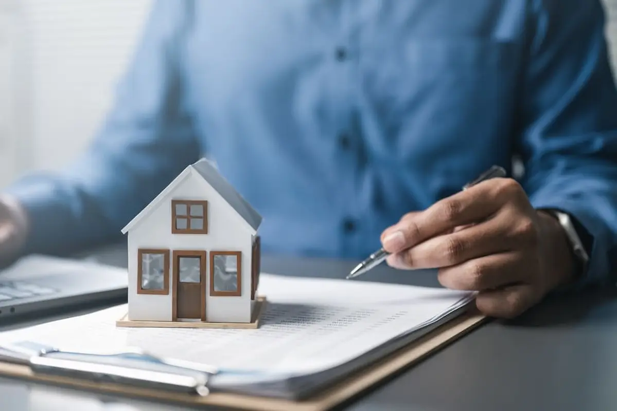 Miniatura de casa sobre documentos contratuais, representando regras e devolução de valores previstas na lei do distrato imobiliário.