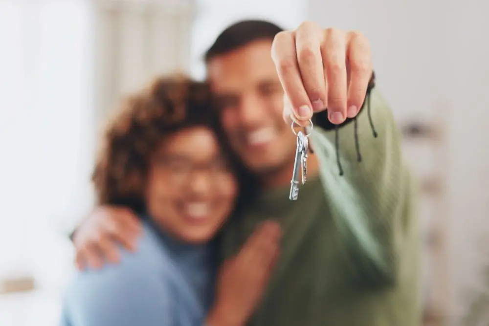 Casal feliz com chave da casa própria comprada no programa minha casa, minha vida.