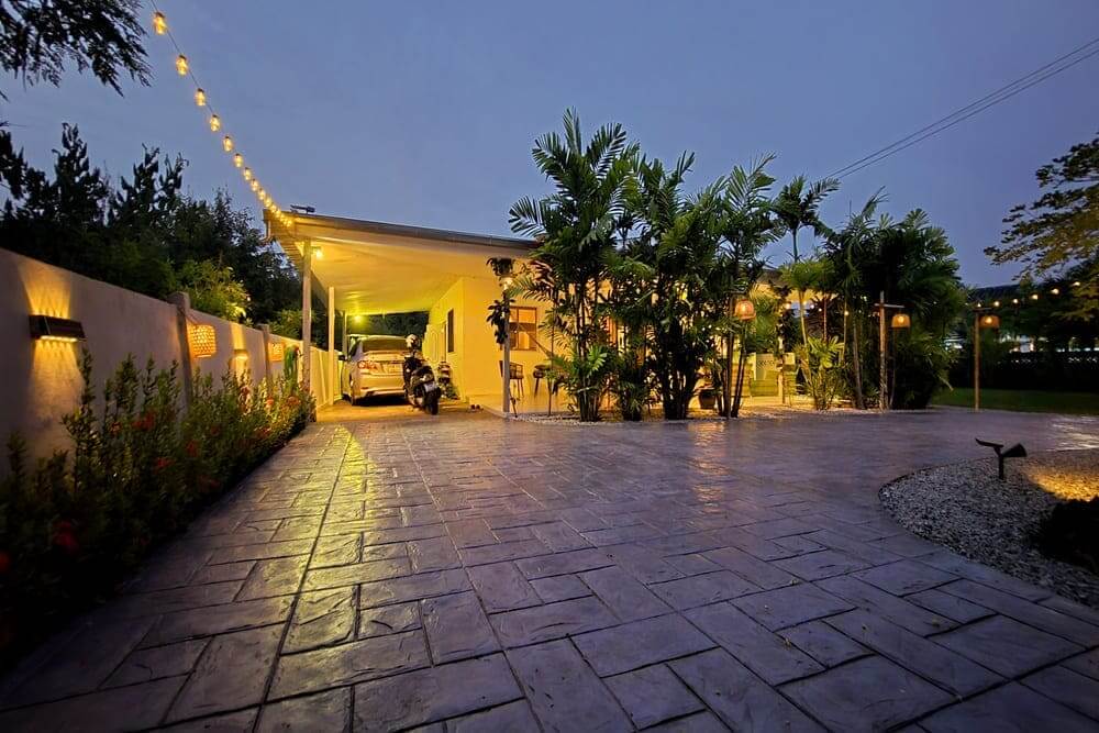 Área externa residencial com piso intertravado antiderrapante e iluminação decorativa, exemplo de qual o melhor piso para área externa em quintais e áreas de acesso.