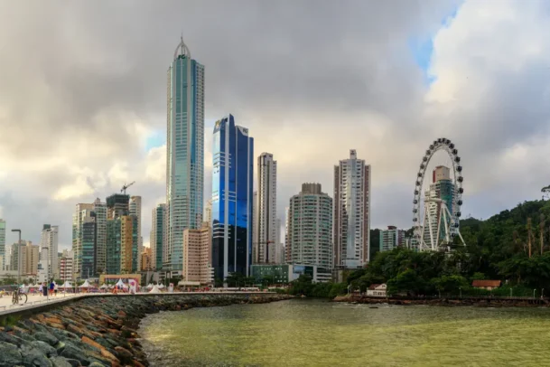 Vista urbana de Balneário Camboriú com arranha-céus, roda gigante e orla, representando cidades com maior IDH do Brasil e alta qualidade de vida moderna urbana.