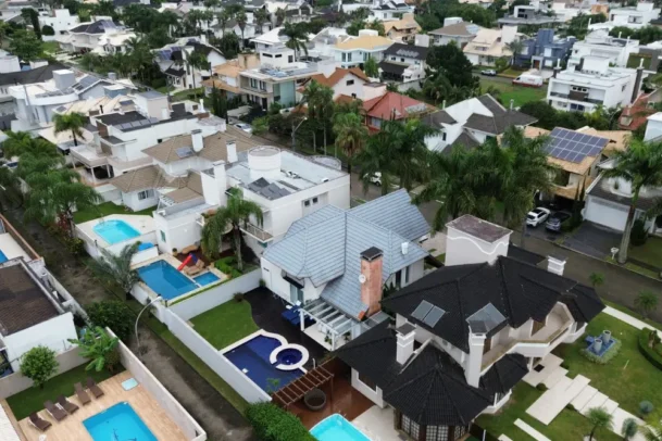 Vista aérea de bairro residencial com casas amplas e piscinas em Florianópolis. A imagem ilustra padrões de moradia e ajuda a entender o florianópolis custo de vida.
