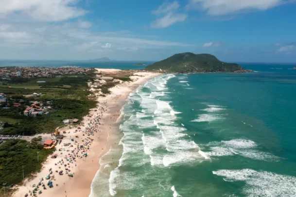 Vista aérea de praia no litoral do Rio Grande do Sul com mar, areia e morros, representando turismo e contexto das maiores cidades do-RS no cenário estadual.