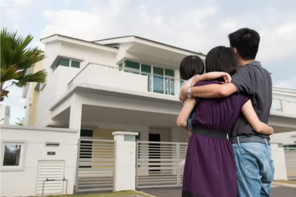 Casal abraçado com seu bebê de colo observando sua nova casa.
