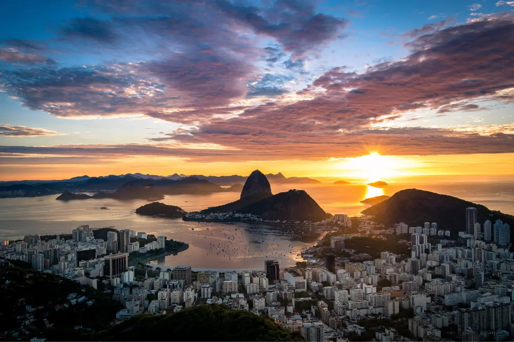 Vista panorâmica do Rio de Janeiro ao pôr do sol, com o Pão de Açúcar e a Baía de Guanabara ao fundo, inspirando quem busca o que fazer no rio de janeiro gastando pouco.