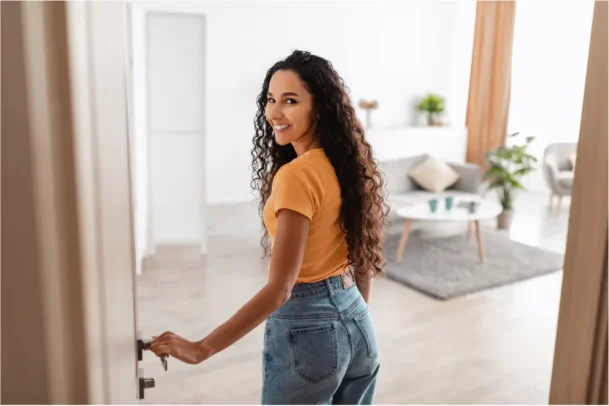Mulher entrando em apartamento iluminado representa diferentes tipos de moradia, independência, aluguel residencial, conquista do primeiro imóvel, conforto, praticidade e rotina urbana moderna.