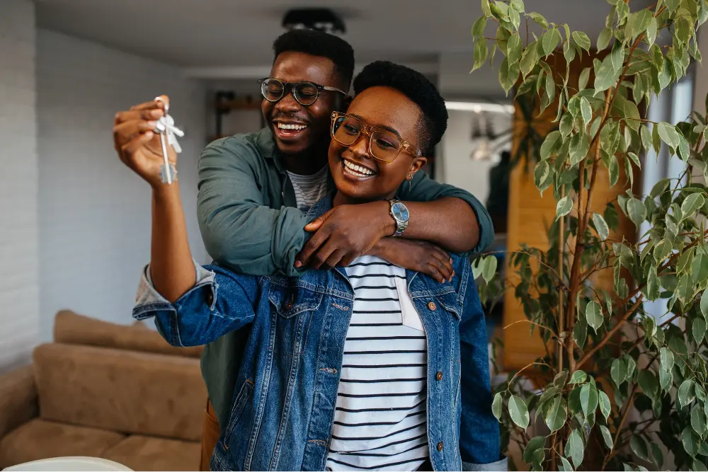 Casal sorrindo segurando chaves dentro de apartamento moderno representa diferentes tipos de moradia, conquista do imóvel próprio, mudança residencial, conforto, segurança e novos começos familiares.