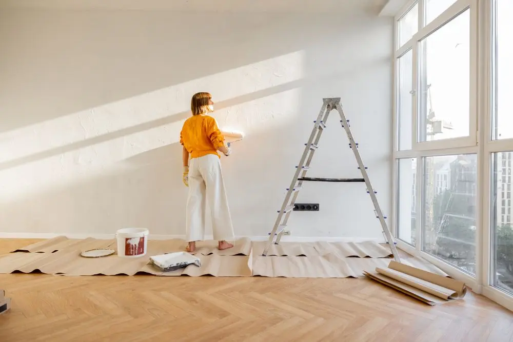 Mulher pintando apartamento, em uma reforma mais simples.