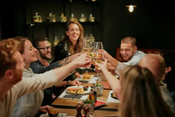 Grupo de amigos brindando com vinho branco em um dos restaurantes na Vila Clementino durante um jantar especial.