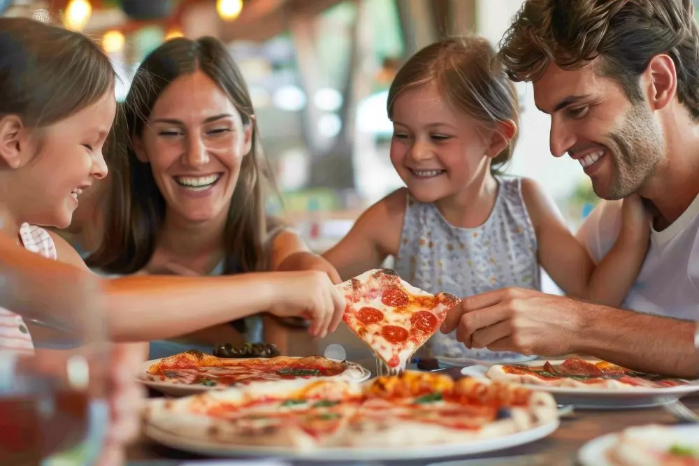 Família feliz comendo pizza em um dos restaurantes da Vila Clementino, em São Paulo.